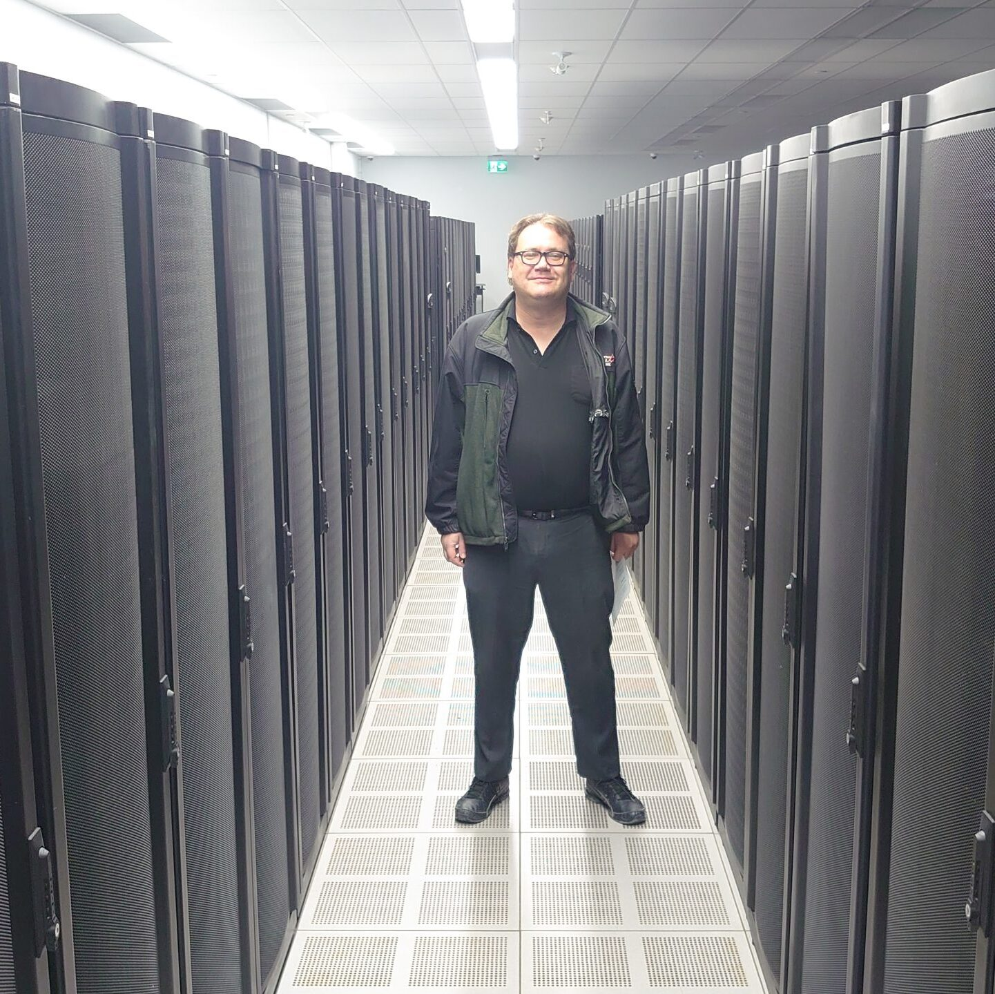 Collin Richard, dirigeant de CJR Digital Solutions, debout dans une allée de serveurs de centre de données.